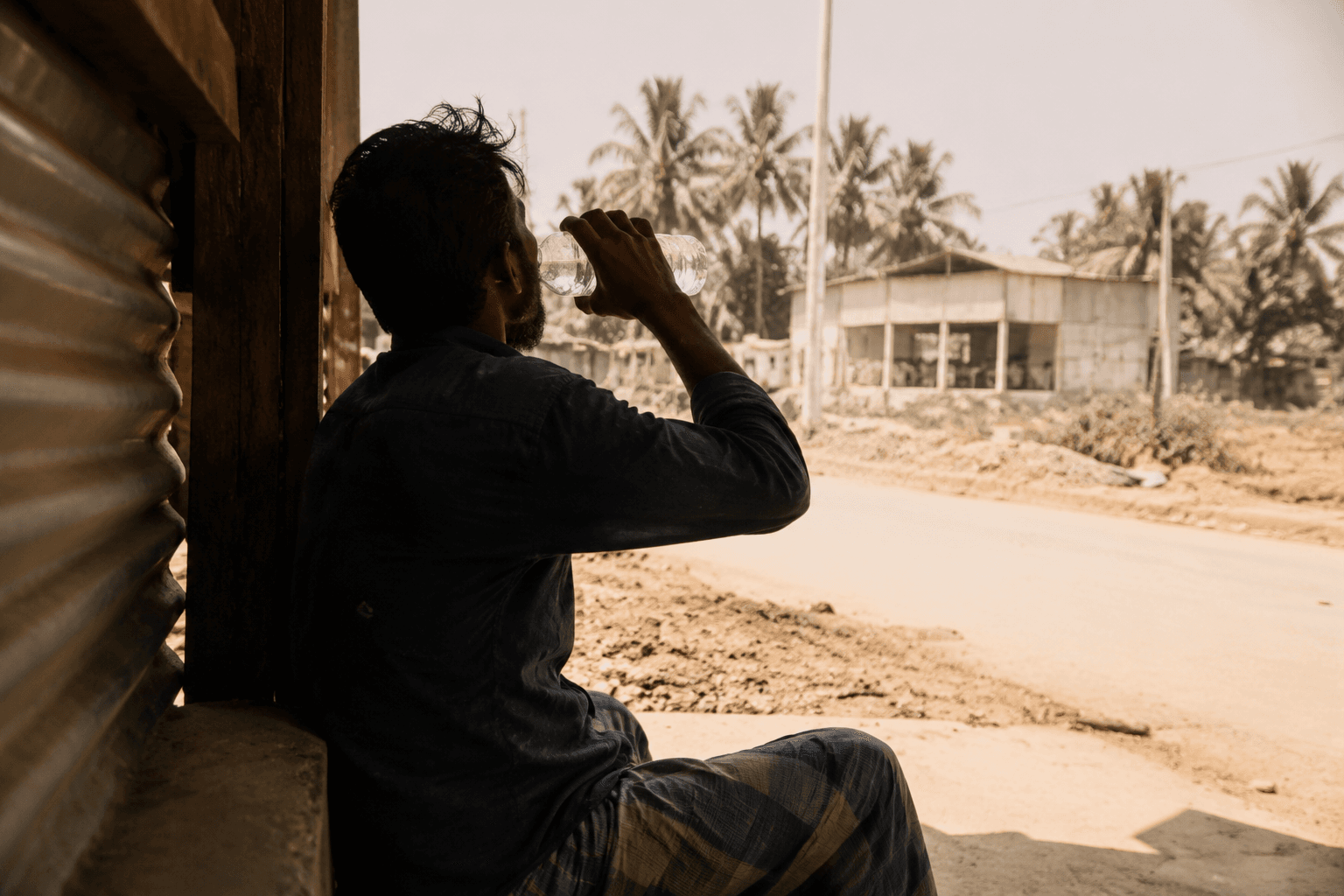 An outdoor worker rests and drinks water during intense heat in Bangladesh